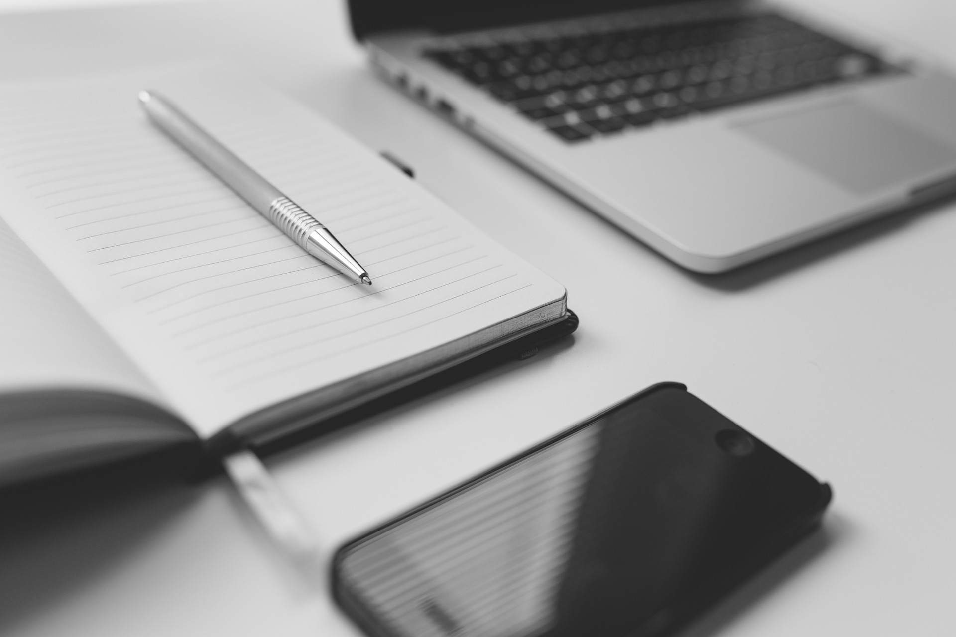 laptop, paper note book with pen, cellphone