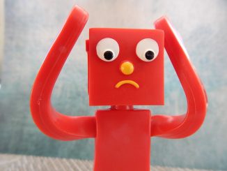 red plastic figurine with sad looking face